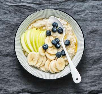 bowl of oatmeal with apple slices, bananas, and blueberries. 