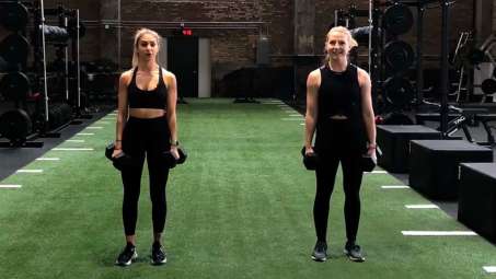two presenting as women standing in black workout tights with weights in each hand