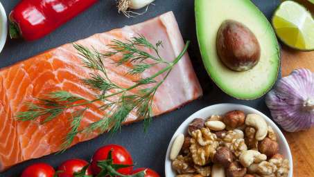 salmon, avocoado, and nuts on a dark table top with an overhead view