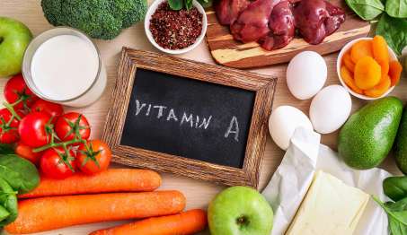 chalk board with Vitamin A written on it with version of food that contain Vitamin A including carrots, tomato's, liver, eggs, apple, etc..