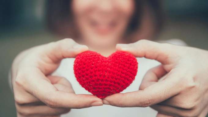 light skinned person holding a crocheted heart in their fingers