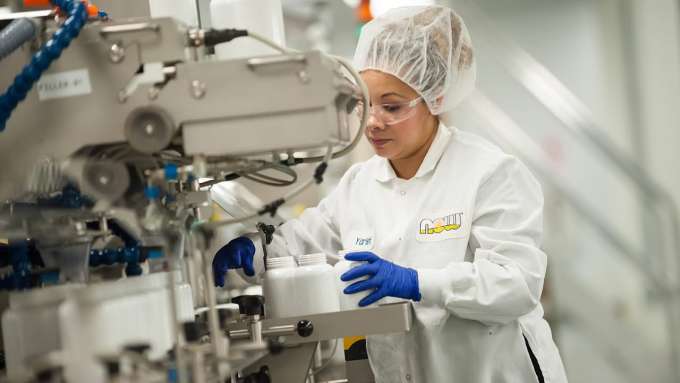 latina woman working with a machine with empty white pill bottles