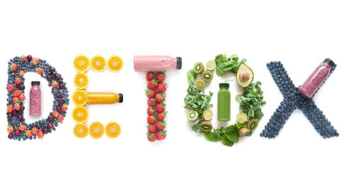 The word "detox" spelled out in fruits, vegetables, and bottles of smoothies