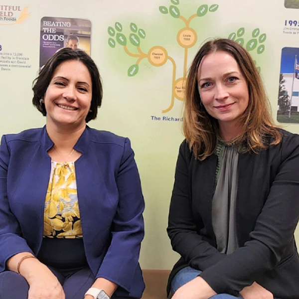 Two people sitting on a bench - Yalda Shokooh, Phd. sitting on the left in purple suit with flowered top, Katie Banaszewski, Phd. sitting on the right with dark sweater over gray top