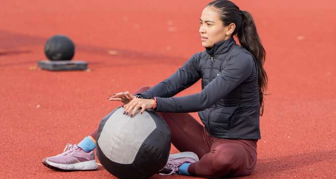 Valery Tobias sitting on track with medicine ball