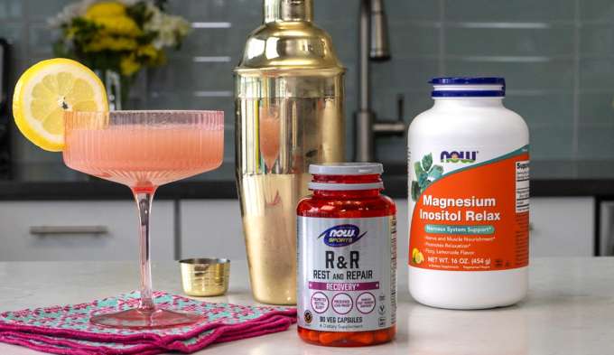 drink glass with pink fluid and lemon slice, gold cocktail shaker, Bottle of NOW Sports Rest & Repair, Bottle of NOW Magnesium Inositol Relax 