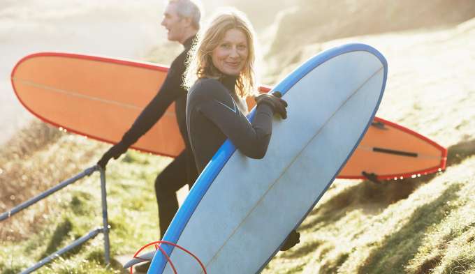 woman and man holding surf boards