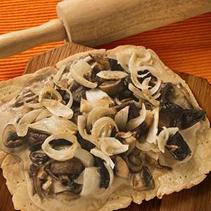 A closeup of mushroom and onion topping a Gluten Free Forager Pizza.