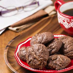 A decorative red and white plate on a wooden table holding Gluten Free Cacao Cookies.