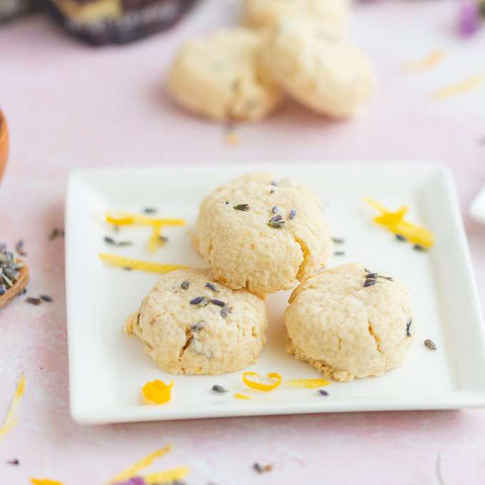 Lemon Lavender Shortbread Cookies on a white plate sprinkled with lavender flowers and Lemon peels