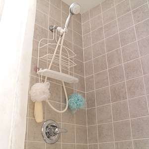 The inside of a shower with brown wall tile