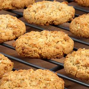 Several Vegan Tropical Oatmeal Cookies on a black wire baking rack on a wooden table.