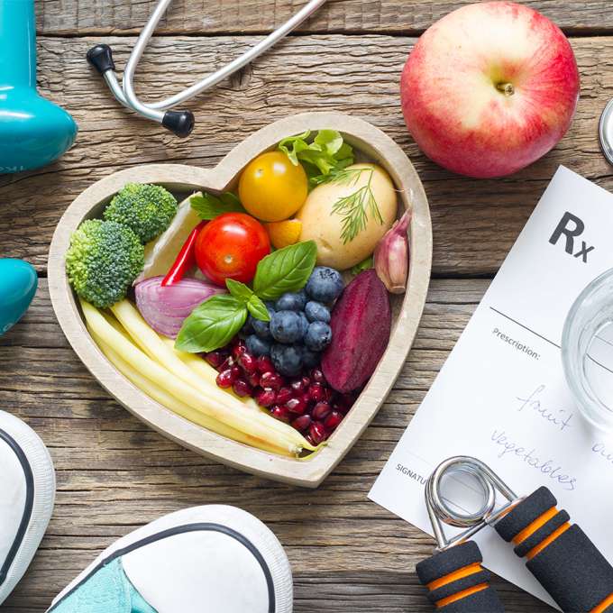 heart shaped container with vegetables and fruits surrounded by stethescope