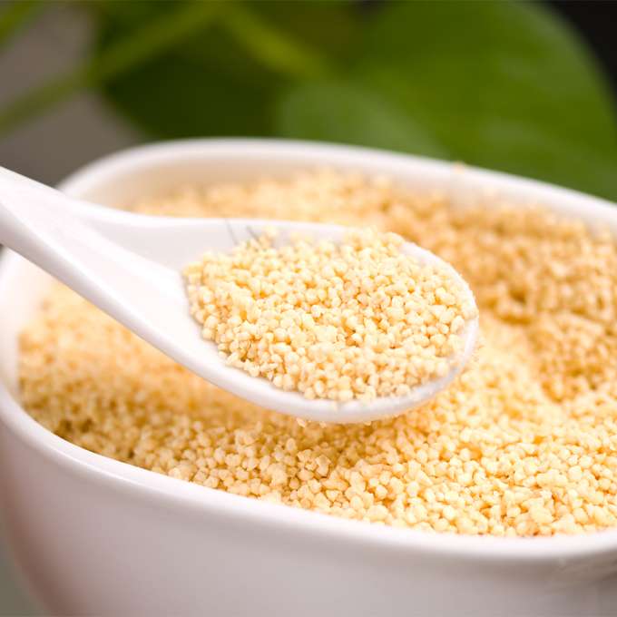 A white ceramic spoon scoops some lecithin out of a white ceramic bowl.