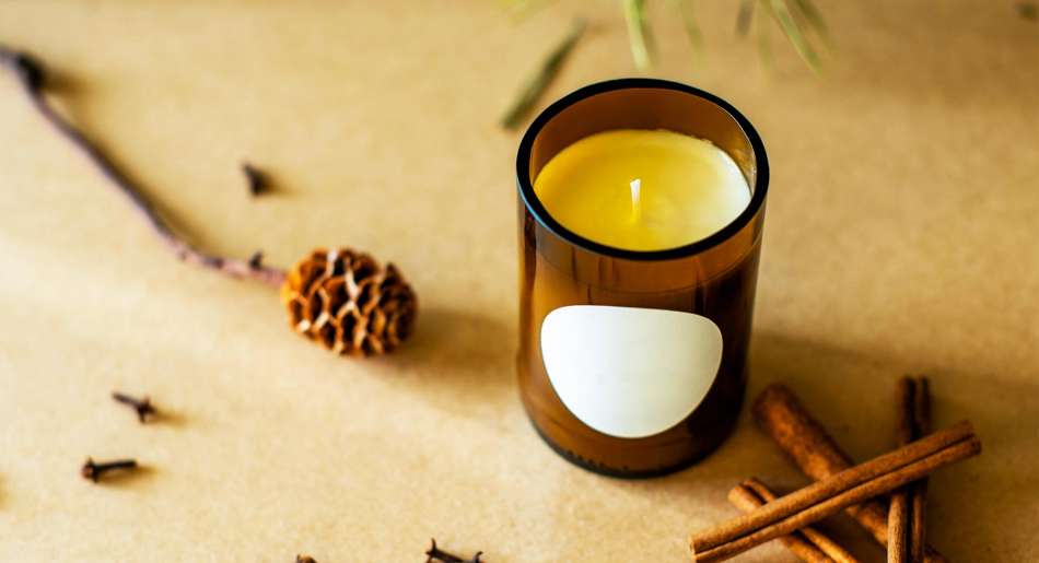 soy candle in a brown glass jar. cinnamon sticks on the table 