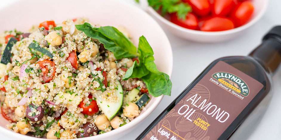 quinoa salad in a white bowl next to a bottle of ellyndale almond oil