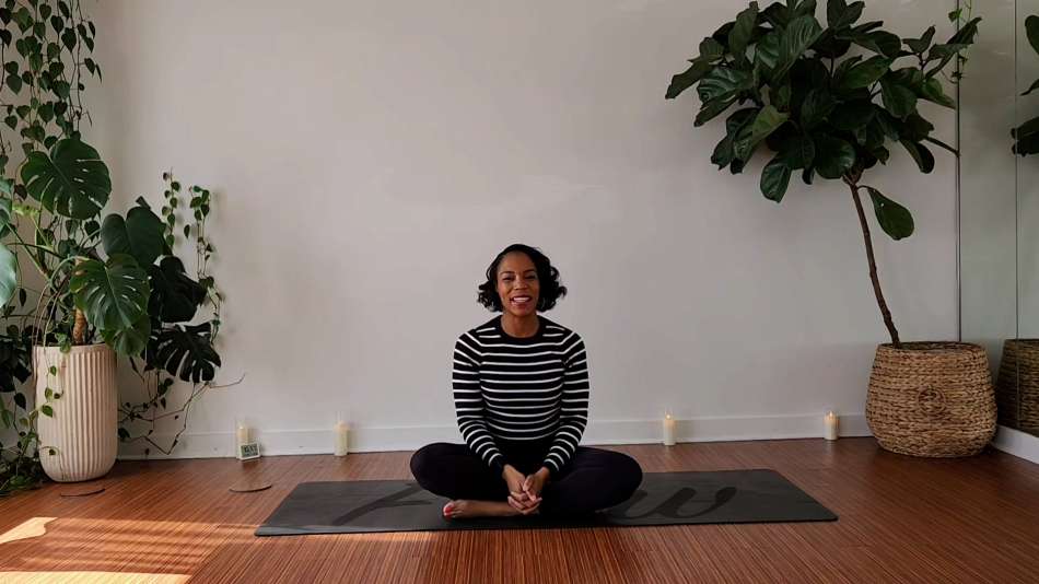 Georgette Dunn sitting cross legged on a black yoga mat 