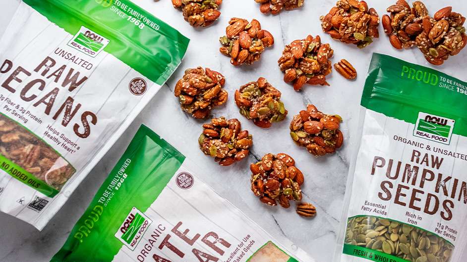 top view of a bunch of Date-Sugar-Nut-Clusters with NOW Raw Pecans, NOW Date Sugar, and NOW Raw Pumpkin seeds around them