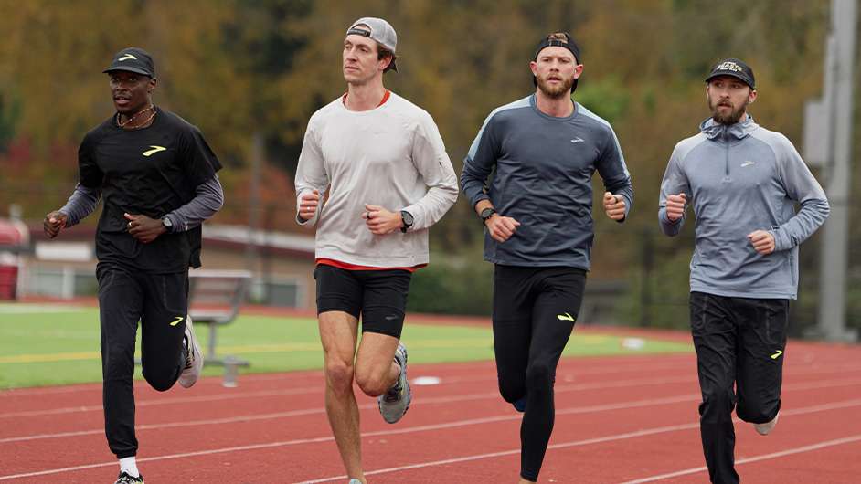 4 males running outdoors on a red track