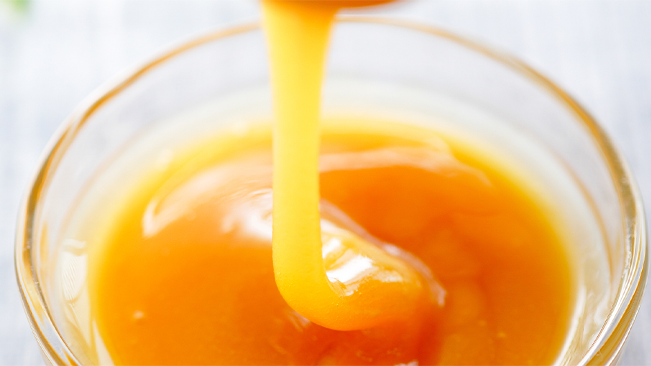 thick orange substance being poured into a clear bowl