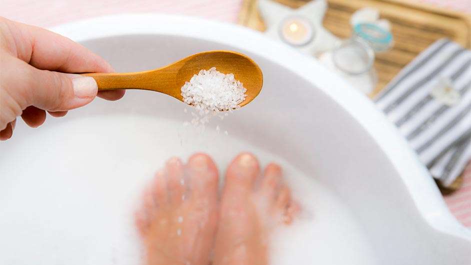 wooden spoon sprinkling foot soak into a bath