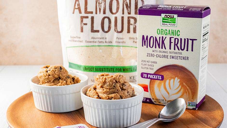 two white ramenkins with Low-Carb-Edible-Cookie-Dough next to NOW Almond Flour and Monk Fruit