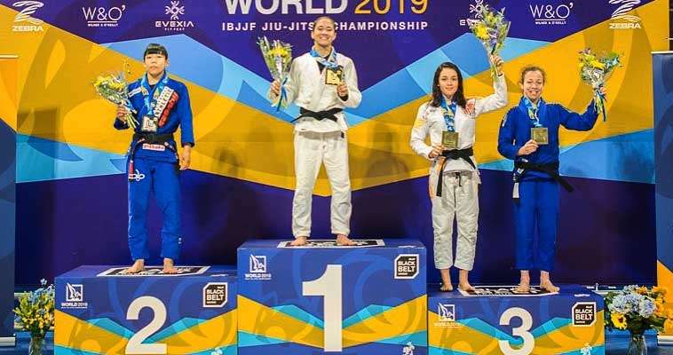 mayssa bastos on podium in number one spot with flowers and medal